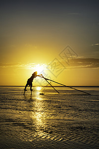 黑影渔民在清晨蓝色天空海滩橙子文化太阳反射旅行渔夫钓鱼背景图片