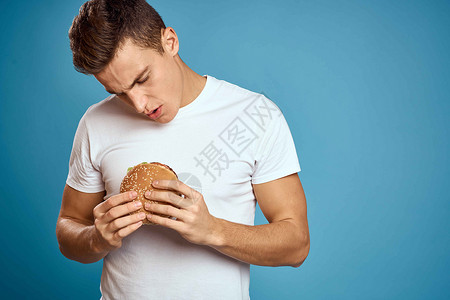 有汉堡和白色T恤 蓝色背景情感的人 用双手探探究 复制空间CopySpace营养成人男人肥胖男性午餐芝士饮食工人男生背景图片