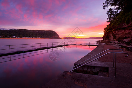 红粉红色黎明天空和岩池的反射图片