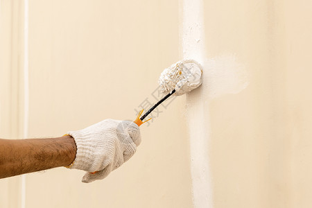 用滚筒在混凝土墙上涂白白色装修男人泥水匠工具液体住宅建造业画家建筑手套背景图片