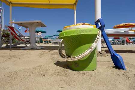 沙桶铲子在阳光明媚的一天 儿童海滩玩具桶 铲子和铲子在沙地上背景