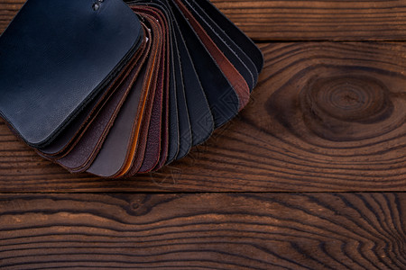 深色木桌上鞋子的皮革样品革质装饰指导装潢家具纺织品风格奢华皮肤艺术背景图片