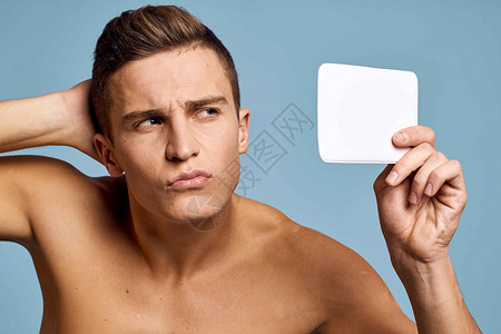 一个男人用蓝背景的眼神 照着镜子看脸温泉男人头发成人男生微笑浴室护理剃须奶油背景图片