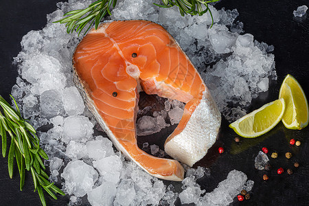 新鲜的鲑鱼牛排 含食料 草药 胡椒和黑底柠檬的鱼片香料烤箱桌子鳟鱼木板食物维生素饮食洋葱寿司背景图片