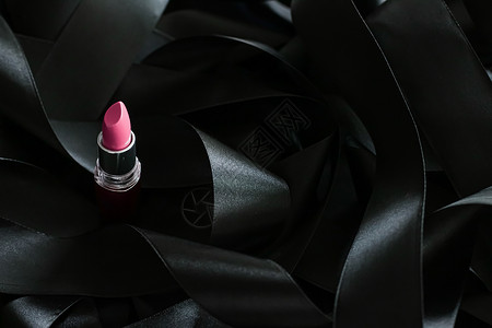 黑色丝绸背景的粉红口红 奢华化妆和美容静物化妆品女士魅力粉色光泽度皮革背景图片