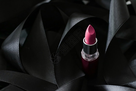 黑色丝绸背景的粉红口红 奢华化妆和美容皮革静物光泽度粉色女士魅力化妆品背景图片