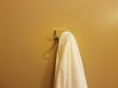 在浴室挂有白毛巾的黄色或橙黄色墙背景图片