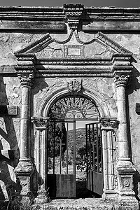 Kefalonia岛被摧毁的东正教教堂门贴水历史性宗教销毁头孢类金属柱子黑与白石头建筑背景图片