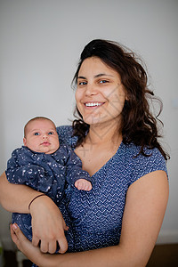 微笑的母亲将她的女婴抱在她的怀里背景图片