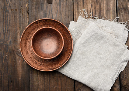 木桌上空的棕色陶瓷盘桌布黏土织物圆形圆圈餐巾乡村制品烹饪厨房背景图片