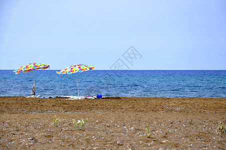 空荡荡的塞浦路斯沙滩上的两把彩色遮阳伞背景