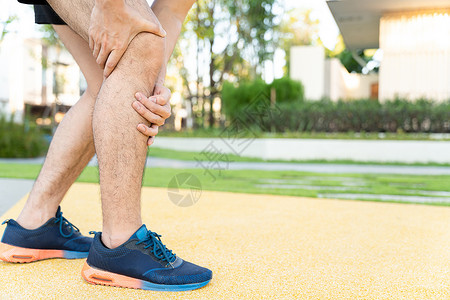 男性运动员腿部受伤和疼痛 手在公园里跑时抓着痛苦的膝盖疾病赛跑者踪迹小牛训练女性治疗慢跑者抽搐伤害背景