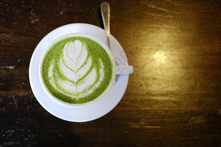 绿色咖啡热辣的日本火柴 绿色茶加拿铁艺术饮料食物咖啡牛奶奶油桌子咖啡店抹茶杯子背景