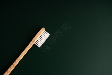 生态友好型牙科健康防菌竹木牙刷 深绿色背景的绿色浴室木头材料工具牙医刷子牙齿纤维卫生口服背景图片