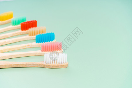 一套由浅绿色背景的竹木制成的环保抗菌牙刷 环保趋势牙齿卫生材料木头刷子生态彩虹牙科工具回收背景图片