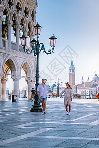 一对夫妇在威尼斯进行城市旅行 欣赏圣马可广场 意大利威尼斯总督府公爵宫的景色 威尼斯的建筑和地标 威尼斯的日出城市景观大教堂教会背景图片