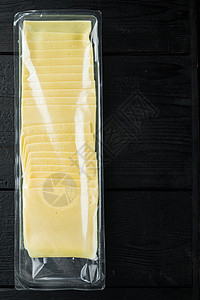 豪达奶酪密封包装的黄奶酪切片 黑色木制桌子上的黄奶酪截片和文本复制空间背景