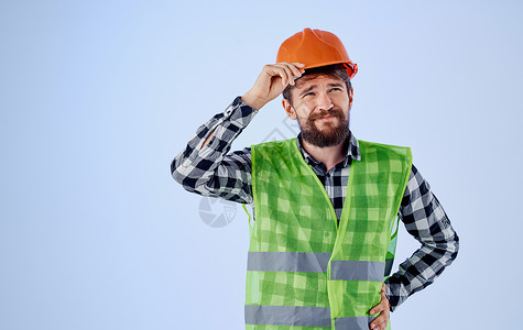 橙色格子身戴橙色硬帽的建筑工人 蓝背景和格子衬衣反射背心工作室修理工工人商业建筑维修领班安全头盔建造背景