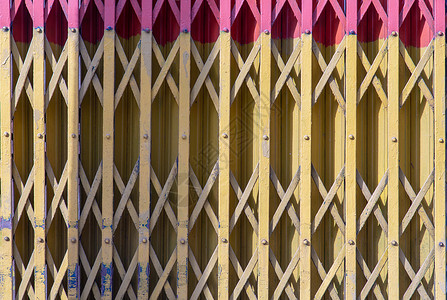 旧的老式铁黄色和粉红色门 钢制折叠门背景