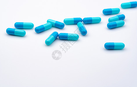在白色背景上传播的蓝色胶囊药丸 医药行业 医疗保健和医学概念 卫生预算 处方类药物 药物错误概念 医药产品 药剂学背景图片