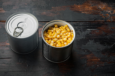 在古老的黑木桌底板上 大量在麦片里罐头中的黄玉米背景图片