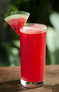 室外桌上的新鲜有机西瓜汁玻璃杯晴天花园果汁桌子红色西瓜玻璃背景图片