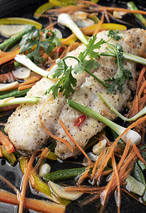 中国风格的中国式蒸鱼片 热盘上加蔬菜推介会电炉食物美食香料鱼片白色热板草药背景图片