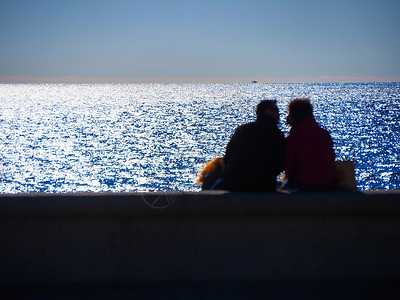 瓦伦丁从坐在海边的后面看到无法辨认的拥抱恋人的模糊图像恋爱太阳日落离别情侣旅行海滩幸福夫妻情怀背景