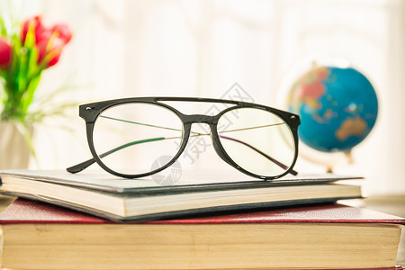 在窗边的硬封面书上贴上眼镜知识桌子商业图书馆风镜光学教科书科学镜片精装背景图片
