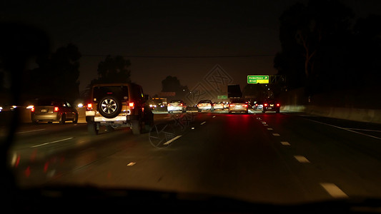从车上看 洛杉矶繁忙的高速公路在夜间 美国加利福尼亚州的大型州际公路 自动在高速公路车道上快速行驶 交通堵塞和城市交通概念窗户旅背景