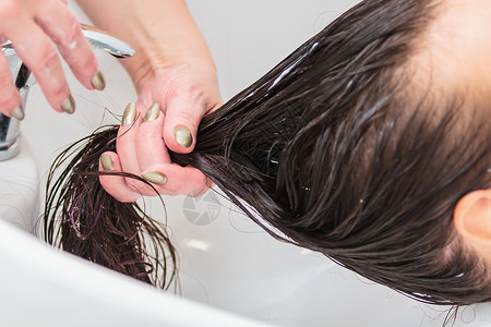 湿手理发师洗了一个头发长在水槽里的女孩的头沙龙发型师润肤温泉客户洗发水治疗服务按摩专家背景