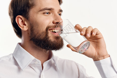 快乐的人喝水 从玻璃杯的水 在光背景白衬衫肖像模型上男人矿物玻璃饮料白色工作室营养口渴男性手指英俊的高清图片素材