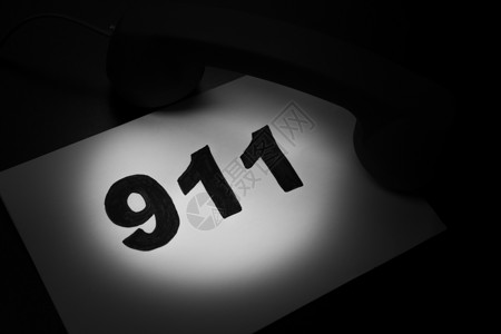 拨打911和紧急呼叫概念 文本911在纸上和电话隔离在黑色邮政警察紧迫感数字记忆拨号写作固定电话援助服务背景图片