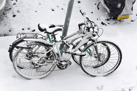 被轮锁停放的飞机两辆被雪雪覆盖的自行车背景