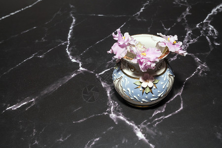 大理石地板上花瓶中的粉红色紫罗兰背景图片
