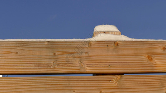 木栅栏上的雪帽季节性积雪白色背景天空蓝色季节晴天高清图片