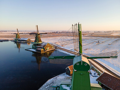 荷兰村的风车雪 冬季历史上的木制风车建筑农村传统桑色天空蓝色村庄反射旅行建筑学背景图片