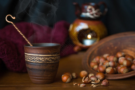 杯子和木质表面散落的坚果栗子木头陶瓷菜肴桌子玻璃食物织物装饰品背景图片