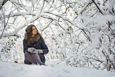 那女孩坐在美丽的雪林里 欣赏这美貌的美丽背景图片