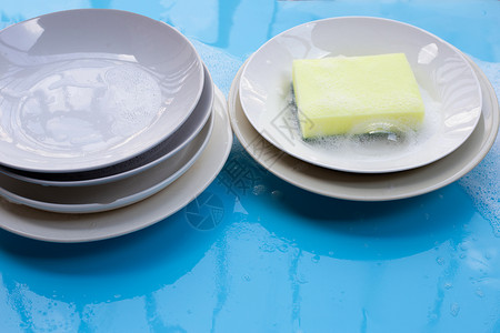 泡沫池用肥皂泡沫在湿蓝色背景上洗碗团体概念食物果汁午餐白色打扫陶器盘子餐具背景