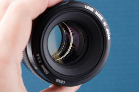 标准照片素材在蓝色背景上持有现代数字式50毫米f 1 4 dslr透镜  有选择性焦点的闭合背景