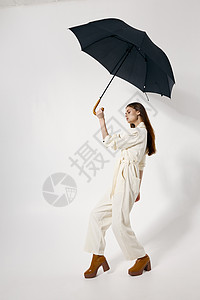 时装时髦的女士 在她的头上戴着露天伞 免受雨褐靴子的挡雨保护;现代风格背景图片