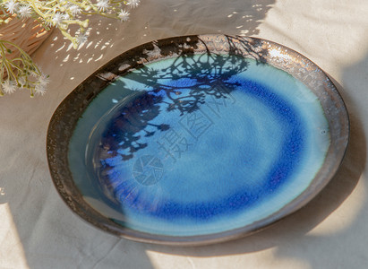 白色纹理桌布上的陶瓷板和花印花布陶器盘子工艺餐具花朵装饰制品蓝色家居背景图片