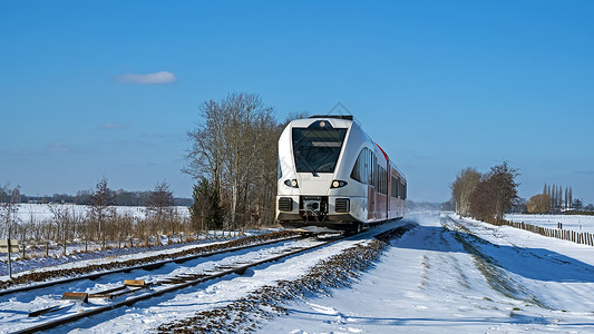 冬季从荷兰出发 在农村开火车去乘火车糖霜民众速度白色场地天气旅行铁路交通铁轨背景图片