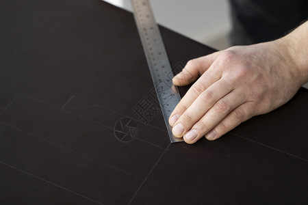 男人的手拿着锥子和金属尺子 在他的工作室里制作皮革钱包 与棕色天然皮革的工作过程 工匠拿着制作工具 在皮革上做标记缝纫桌子商业裁腰带高清图片素材