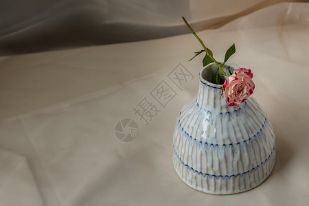 铜色手工陶瓷花瓶和腮红纹理桌布上的玫瑰花材料热情工艺艺术陶器礼物家居餐具潮人织物背景图片