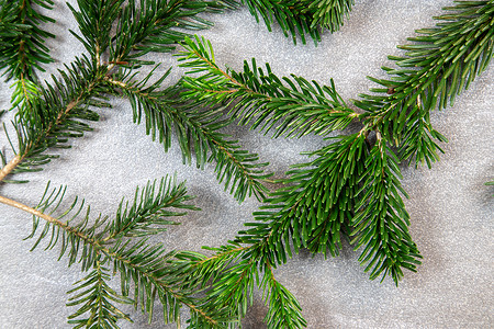 深灰色大理石背景上带有诺德曼冷杉树枝的圣诞主题纹理背景背景图片