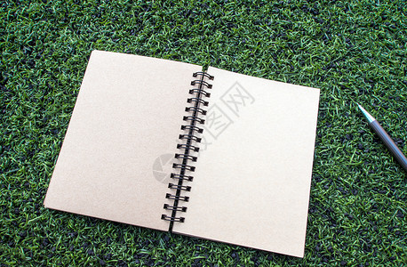 螺旋草笔印在人工地盘上的纸螺旋笔笔记本空白牛皮纸文档铅笔地毯绿色棕色日记草地草皮背景