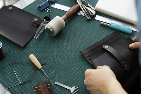 男士手在他的工作室里制作皮革钱包 与棕色天然皮革的工作过程 拿着制作工具的工匠配饰剪刀皮艺缝纫皮肤机器裁缝商业职业手工材料高清图片素材
