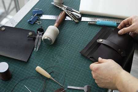 男士手在他的工作室里制作皮革钱包 与棕色天然皮革的工作过程 拿着制作工具的工匠拳头做工作坊剪刀皮肤锥子皮匠桌子缝纫鞋匠鞋类高清图片素材